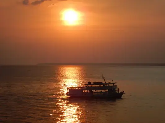 Barco navegando no Rio Amazonas no pôr do sol, em Manaus