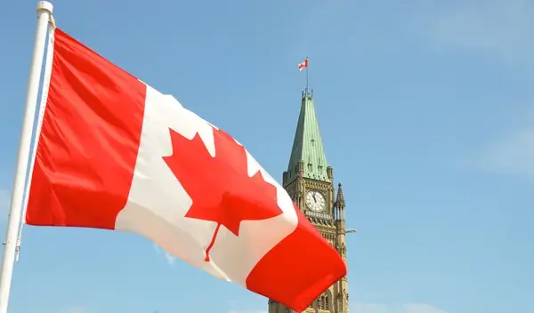 bandeira do canadá em primeiro plano com torre ao fundo