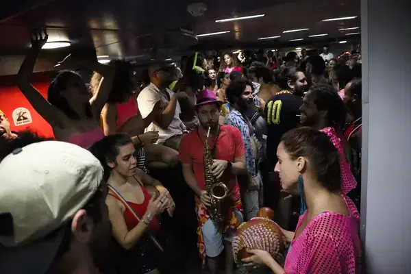 Pessoas fantasiadas em estação de transporte durante o carnaval