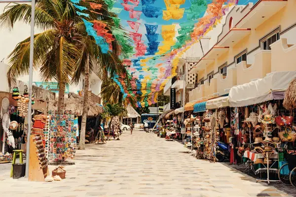 pessoas andando na rua colorida com bandeirinhas penduradas no céu
