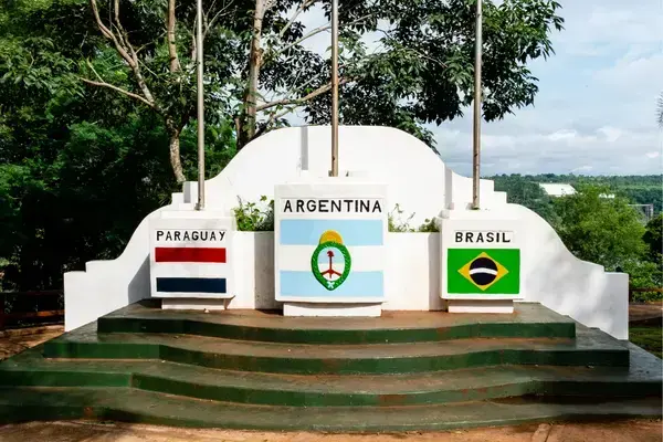 a esquerda a bandeira do Paraguai, no centro a bandeira da Argentina e na direita a bandeira do Brasil no ponto dos 3 marcos