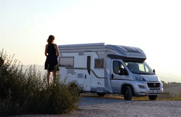 uma mulher ao lado de um motorhome