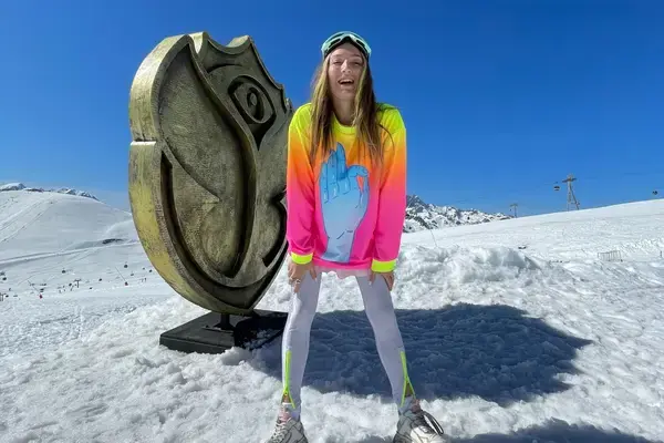 Mulher nos Alpes d'Huez na França em frente a placa com a logo do festival Tomorrowland
