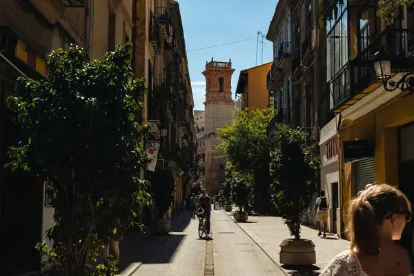 homem andando de bicicleta na rua estreita cheia de predios