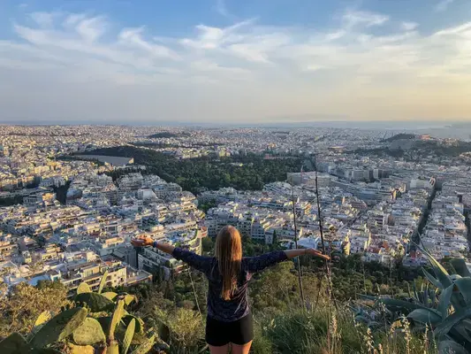 mulher de braços abertas olhando cidade do alto