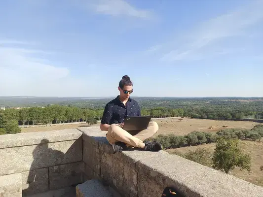 homem trabalhando em notebook em cima de muro