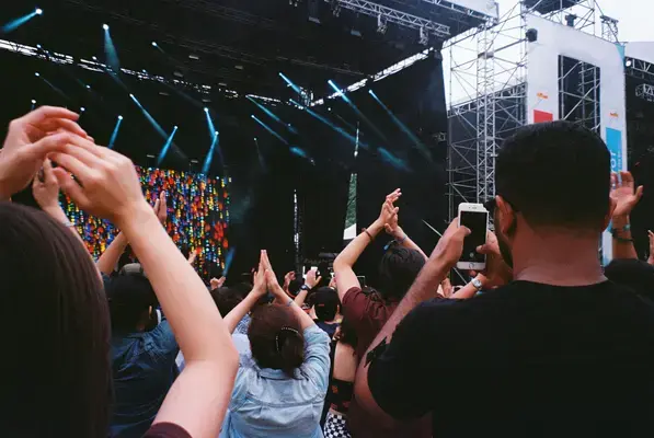Pessoas batendo palmo em frente ao palco em show