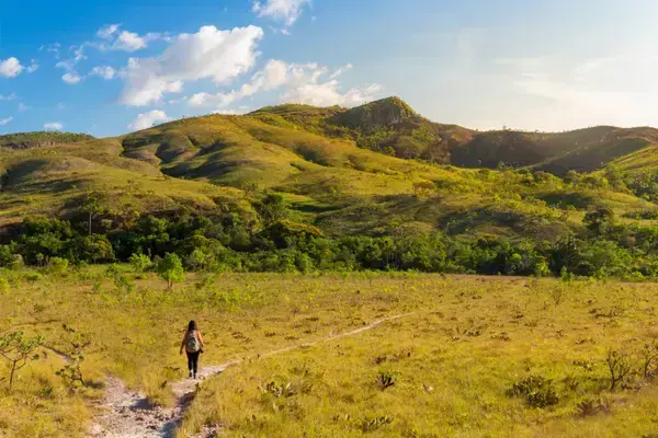Mulher caminhando entre morros da Chapada dos Veadeiros