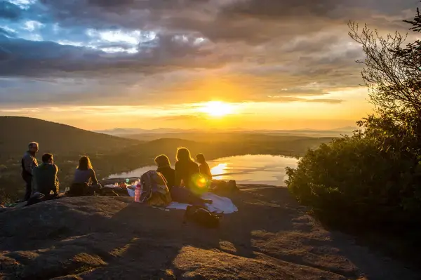 Família vendo o pôr do sol no alto de uma montanha