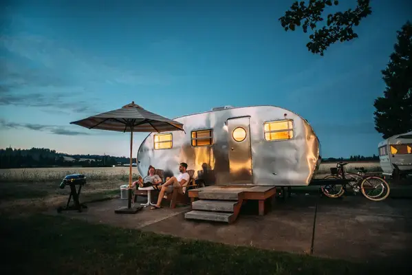 Família em mesa em frente a trailer de viagem