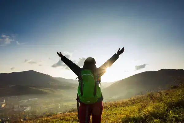 Mulher com mochila nas costas em paisagem montanhosa