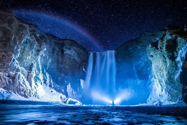 pessoa em frente a cachoeira durante a noite sob o céu estrelado