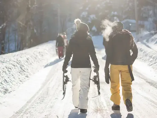 Pessoas caminhando na neve com roupa para esportes de inverno