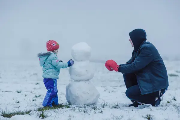 Mãe e filha fazendo um boneco de neve