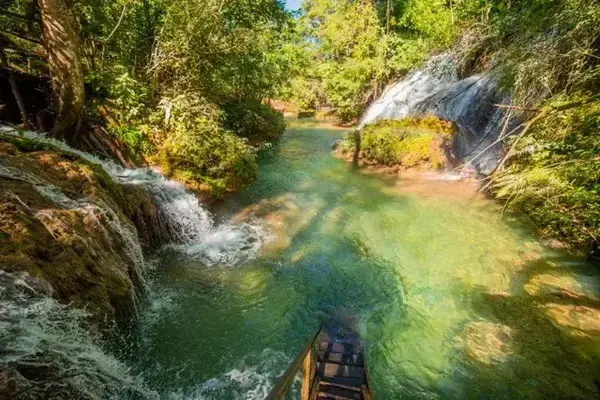 imagem da cachoeira em tom verde e sol refletido na água