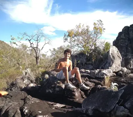 um menino sorrindo em cima de umas pedras na chapada dos veadeiros