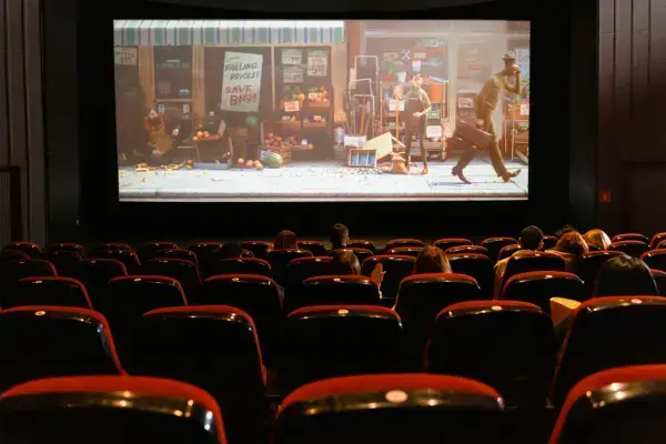 Sala de cinema mostrando a tela e pessoas assistindo nas poltronas