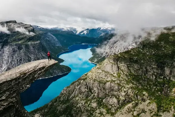 Pessoa em cima de pedra admirando a vista em Trolltunga, Noruega