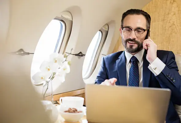 Homem falando no celular e usando o notebook em avião