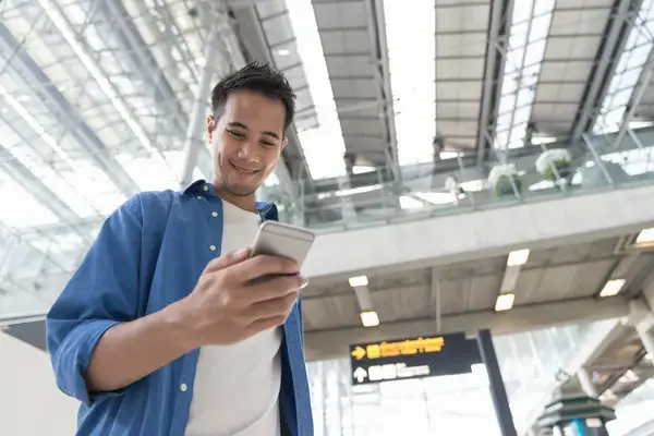 Homem olhando celular em aeroporto