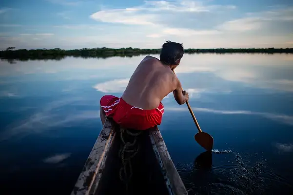 Indígena remando em barco no rio