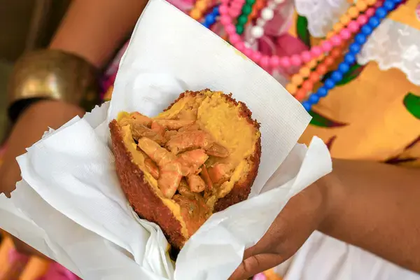 mãos segurando um prato que contém comida típica da culinária afro