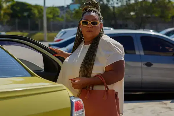 mulher preta com oculos e roupas claras entrando no taxi