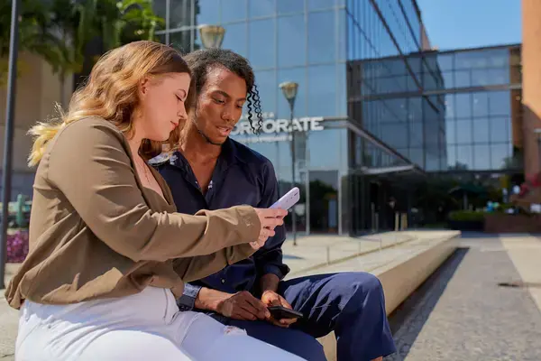 duas pessoas conversando enquanto uma segura o celular explicando para a outra