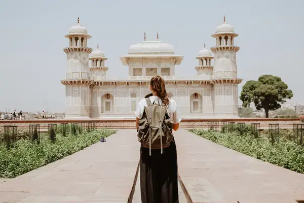 Mulher com mochila nas costas em frente a templo na Índia