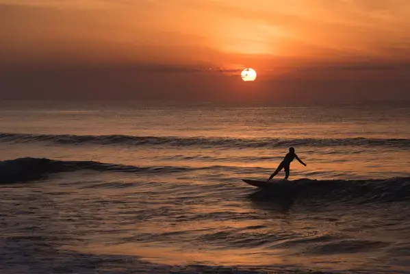 Pessoa surfando no pôr do sol de Ubatuba