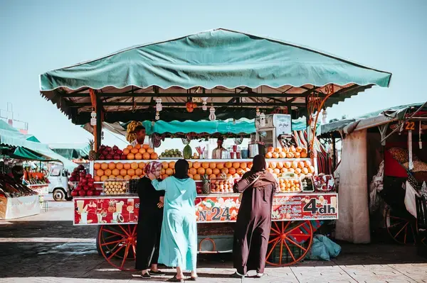 grupo de pessoas ao lado de um carrinho de frutas