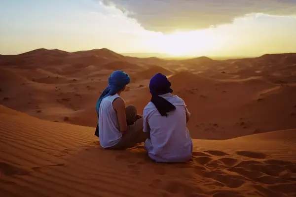 duas pessoas sentadas nas dunas de areia