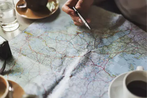 Mapa em cima de mesa com xícaras e itens ao redor