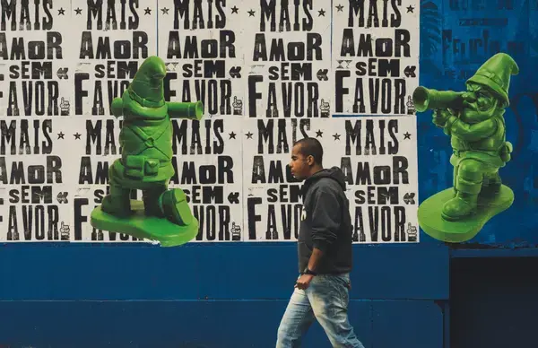 Homem caminhando em frente a mural com grafite na Avenida Paulista