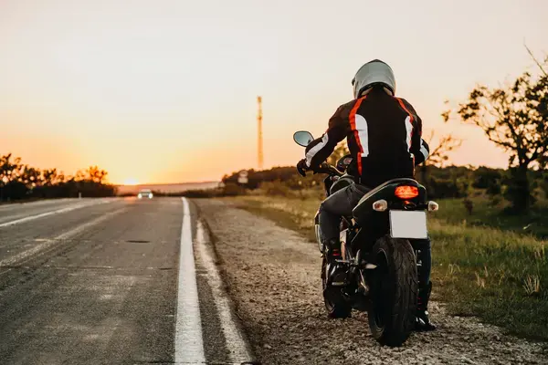 Homem em moto em acostamento de estrada (Fonte: Adobe Stock)