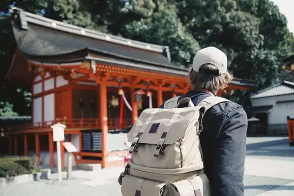Homem com mochila passando em frente a templo no Japão Fonte: Unsplash