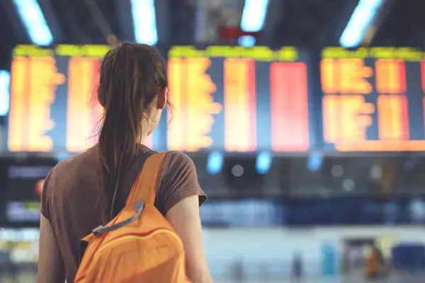 Mulher olhando painel de voos em aeroporto (Fonte: Adobe Stock)