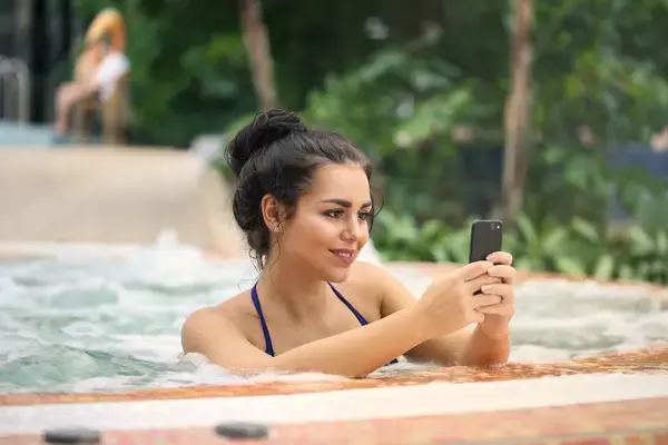 foto-de-uma-mulher-na-jacuzzi-usando-um-smartphone
