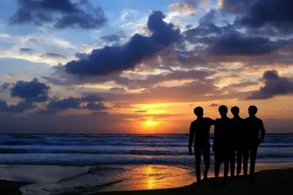 Silhueta de amigos em praia ao por do sol