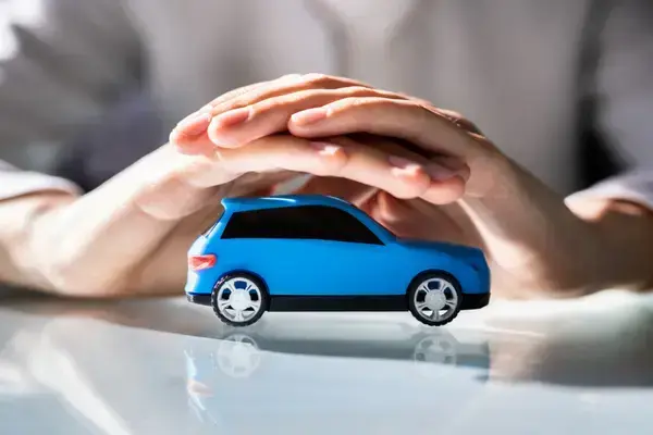 uma mão simbolizando proteção em sobre um carro pequeno para simbolizar um seguro
