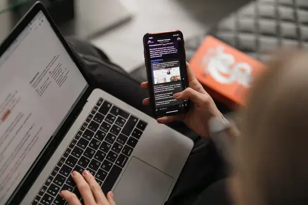 Mulher usando notebook e celular (Fonte: Unsplash)