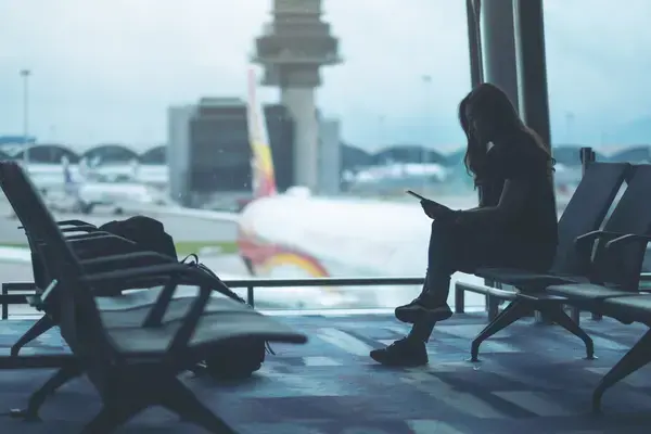 mulher com a cabeça baixa sentada no banco do aeroporto