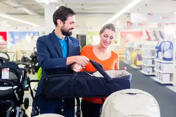 homem e mulher segurando um bebê conforto