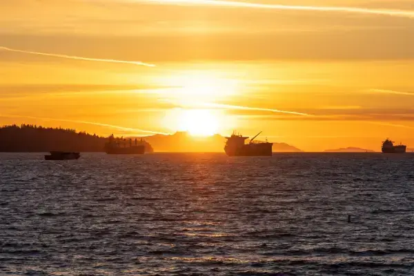 Por do sol na English Bay Beach com silhueta de navios no mar