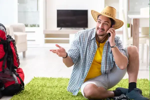 homem sentado na sala enquanto faz as malas