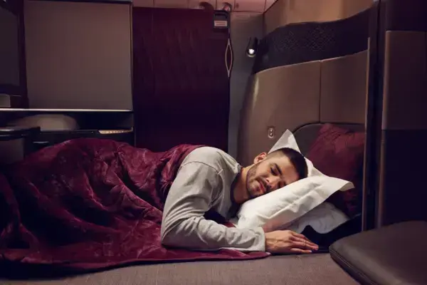 Homem dormindo em poltrona na classe executiva (Fonte: Qatar Airways/Reprodução