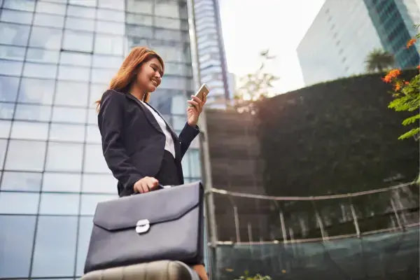 mulher segurando em uma mão a mala e na outra o celular