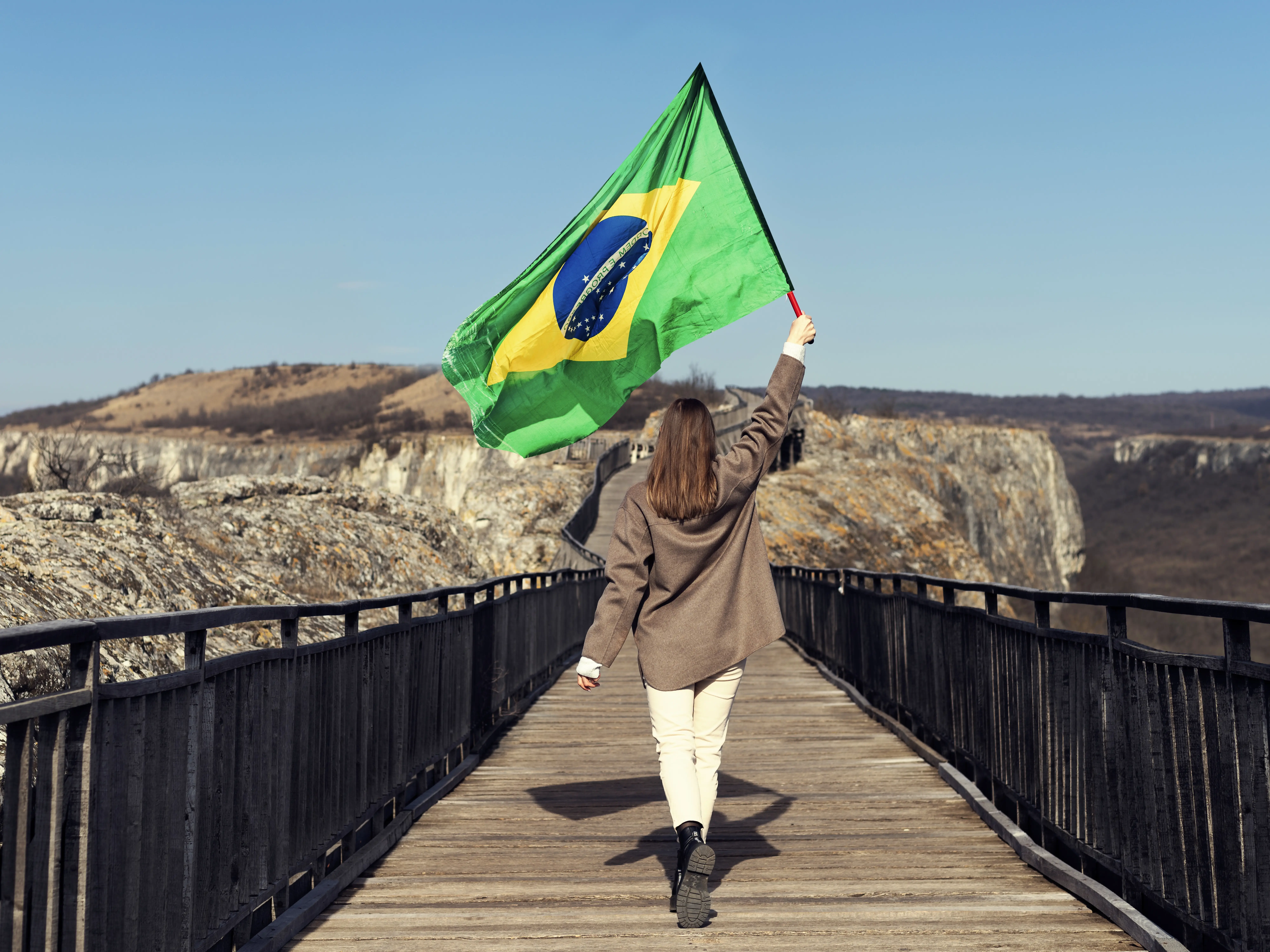 Mulher de tiro completo segurando a bandeira brasileira