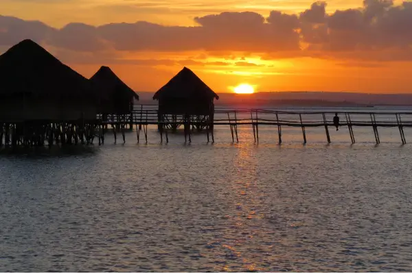 Por do sol refletindo na água do mar de praia de Moçambique