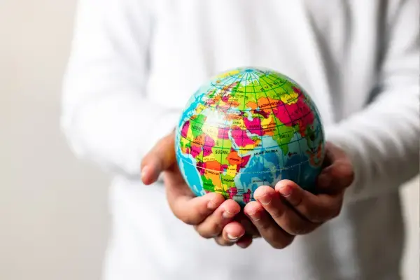 um par de mãos segudando um globo terrestre em miniatura